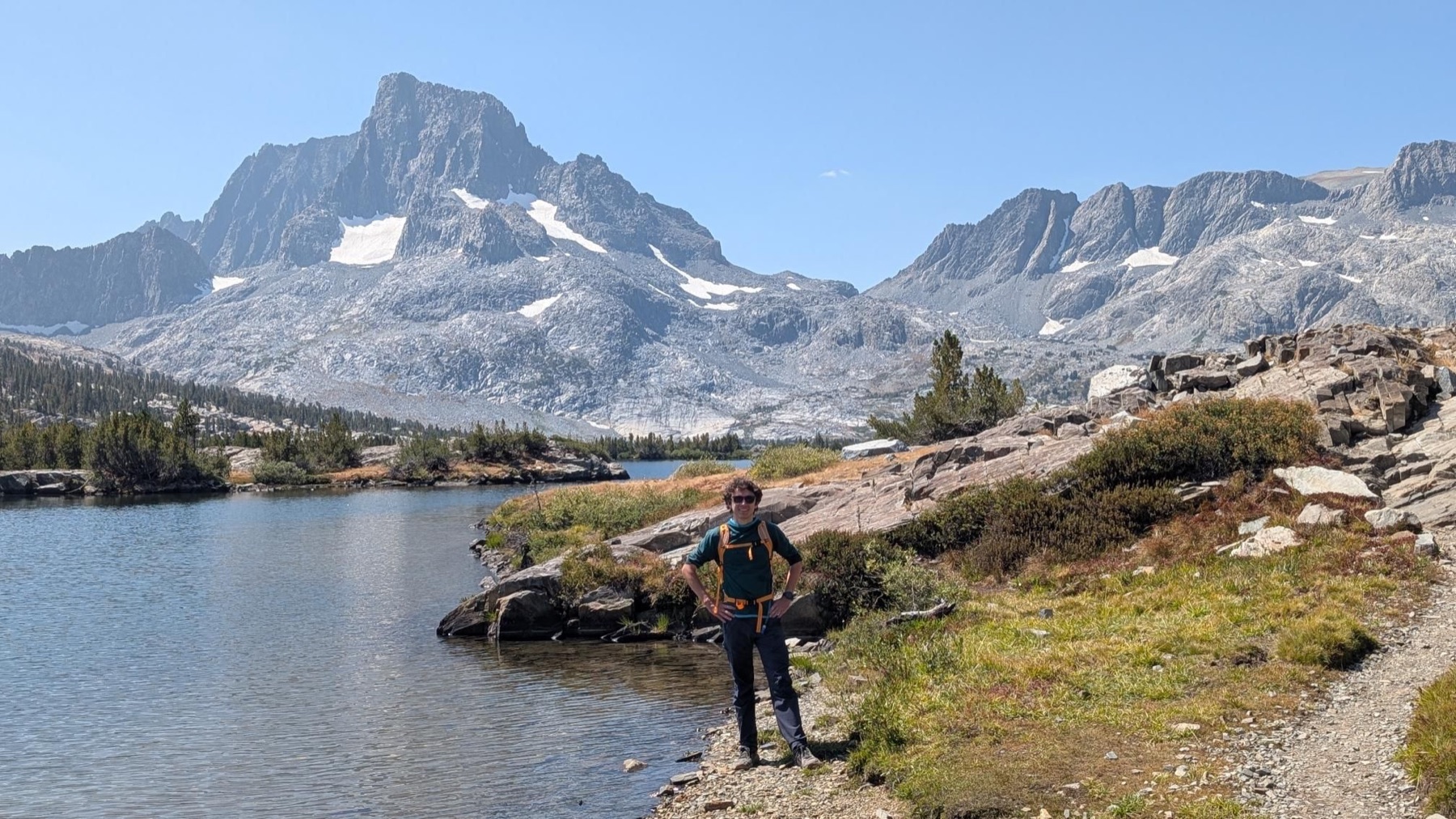 Hiker beside an alpine lake beneath Banner Peak
